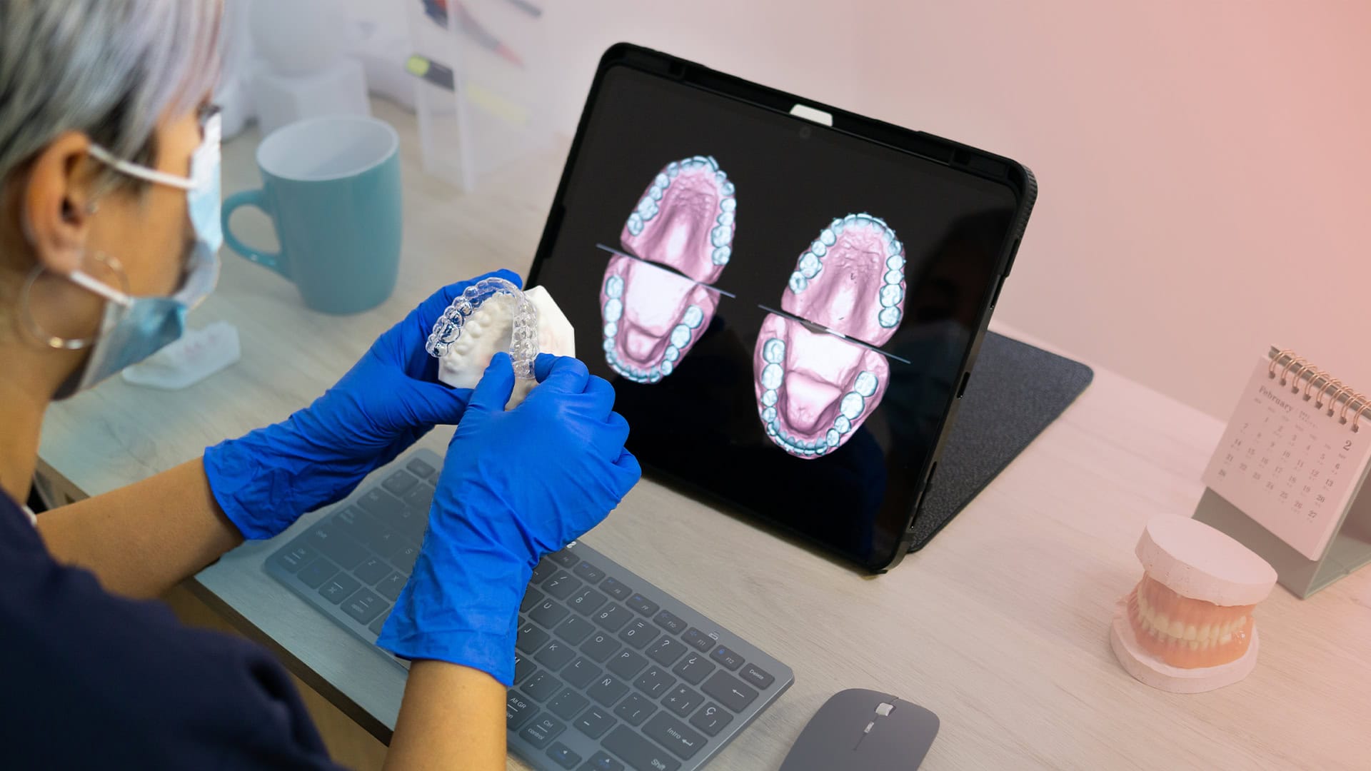 Eldivenli klinisyen, taranmış diş arklarını gösteren tabletin yanında şeffaf plak tutuyor